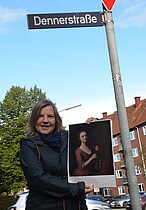 Simone Dornia an der Dennerstraße mit einem Gemälde von Catharina Denner, das ihr Vater Balthasar malte. Allein nach ihm ist die Straße bisher benannt