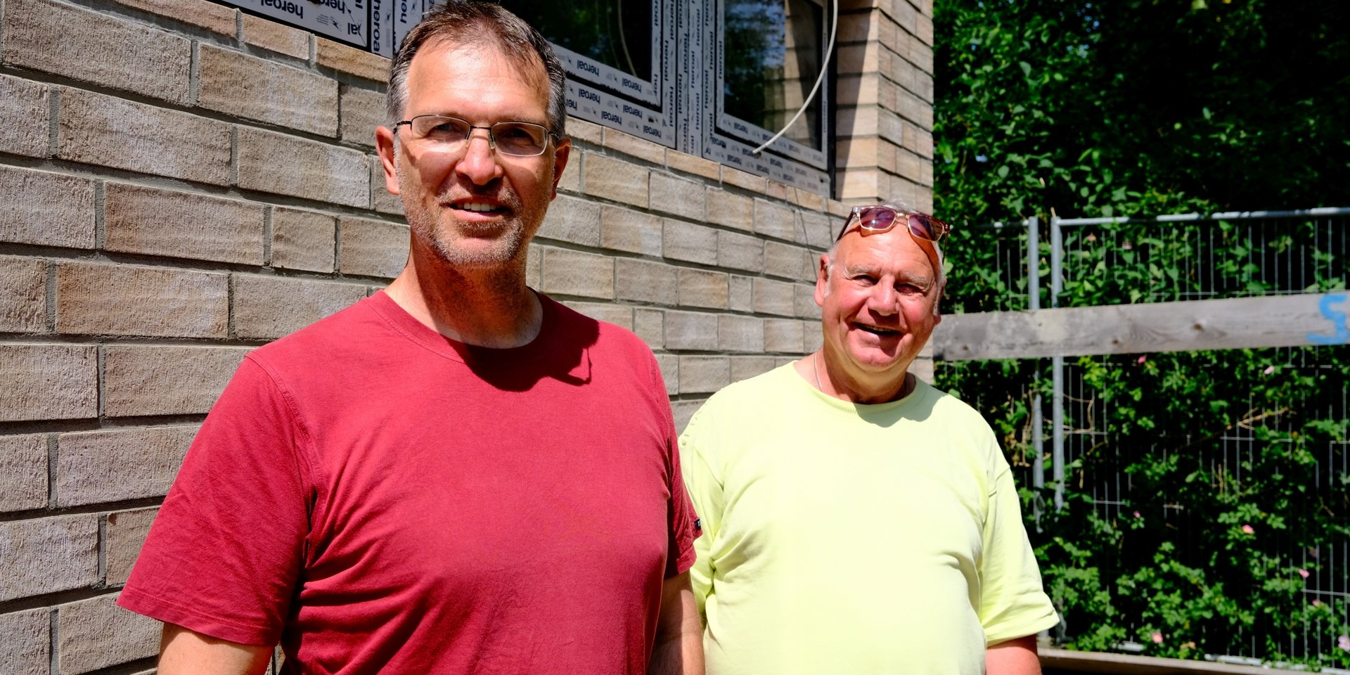 Oliver Camp (GRÜNE, l.) und Rüdiger Wendt (SPD, r.) neben der neuen Sporthalle der Adolph-Schönfelder-Schule direkt an der Dehnhaide
