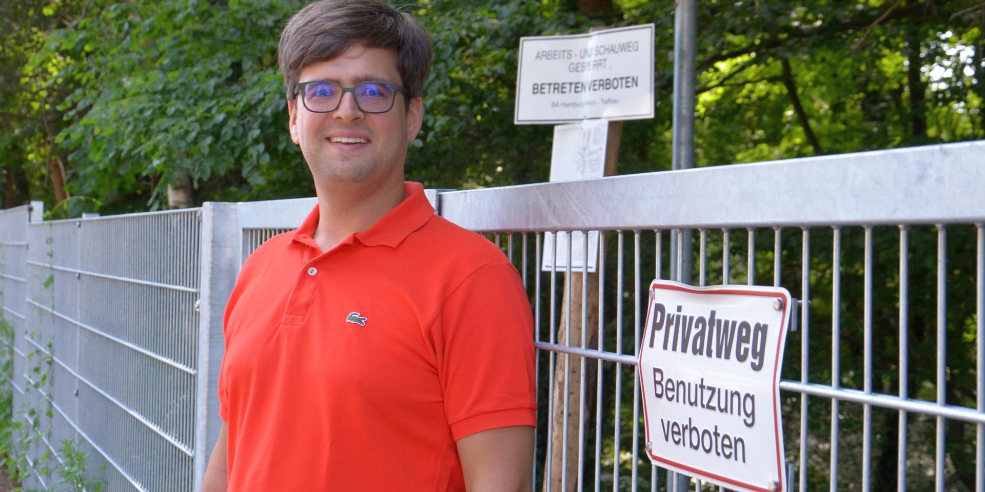 Timo B. Kranz (GRÜNE) am Tor, das derzeit noch in der Straße Tarpen den Weg am Bachufer versperrt