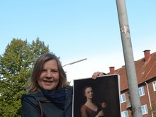 Simone Dornia an der Dennerstraße mit einem Gemälde von Catharina Denner, das ihr Vater Balthasar malte. Allein nach ihm ist die Straße bisher benannt