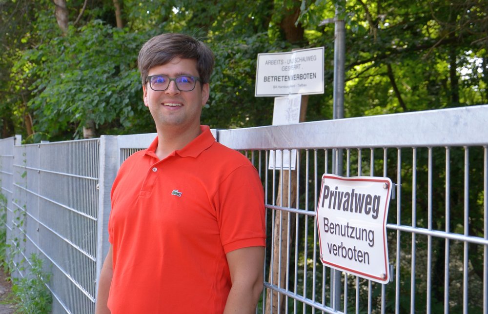 Timo B. Kranz (GRÜNE) am Tor, das in der Straße Tarpen den Weg am Bachufer versperrt